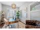 Bright office offers plantation shutters, modern chandelier, glass desk and leather chair at 4615 E Navigator Ln, Phoenix, AZ 85050