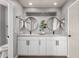 Elegant bathroom with a double vanity, round mirrors, white cabinets and dark hardware at 5302 W Poinsettia Dr, Glendale, AZ 85304