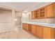 Home wet bar features wooden cabinetry, a wine rack, and tile flooring with a view to the bedroom at 664 W Silver Reef Ct, Casa Grande, AZ 85122