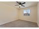 Cozy bedroom featuring neutral carpet, a ceiling fan, and a view from the window at 7008 W Sierra St, Peoria, AZ 85345