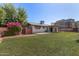 Spacious backyard with lush lawn, patio, and a view of the home's updated exterior at 8501 E Malcomb Dr, Scottsdale, AZ 85250