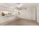 Spacious living room with carpeted area leading to a tiled kitchen featuring a breakfast bar and bright white finishes at 8501 E Malcomb Dr, Scottsdale, AZ 85250