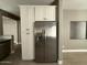 Stainless steel refrigerator and white cabinets in the kitchen area with wood-look floors and neutral paint tones at 15334 W Acapulco Ln, Surprise, AZ 85379