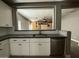 White kitchen cabinets paired with dark counters, stainless steel dishwasher and sink, creating a sleek design at 15334 W Acapulco Ln, Surprise, AZ 85379