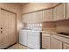 Bright laundry room featuring a washer, dryer, storage cabinets, a built-in sink, and tile flooring at 16927 E Trojan Ct, Fountain Hills, AZ 85268