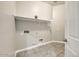 Functional laundry room with built-in shelf and tile flooring at 18207 W Sells Dr, Goodyear, AZ 85395