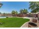 Lush backyard with well-maintained artificial grass, mature trees, and a fenced pool area at 1847 W Leah Ln, Gilbert, AZ 85233