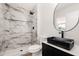 Contemporary bathroom featuring a marble tile shower, sleek black accents, and a modern sink at 2331 E Delgado St, Phoenix, AZ 85022