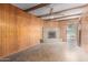 Living room features wood paneling, a stone fireplace, exposed beams, and a ceiling fan at 3302 W Turney Ave, Phoenix, AZ 85017