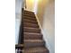 Carpeted staircase with a black railing and white wall, leading to the upper level of the home at 4236 S 46Th Pl, Phoenix, AZ 85040