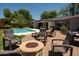 Backyard oasis featuring a sparkling pool, a cozy fire pit, and multiple seating areas for outdoor relaxation and enjoyment at 5438 E Avalon Dr, Phoenix, AZ 85018