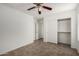 Bright bedroom features a ceiling fan, neutral paint and floors, closet, and open doorway at 6515 W Hughes Dr, Phoenix, AZ 85043