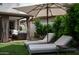 Lounge chairs with white cushions and a cantilevered umbrella offer a relaxing seating area by the lawn at 8068 E Del Trigo Rd, Scottsdale, AZ 85258