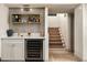 Modern basement bar featuring a beverage cooler, gold fixtures, and adjacent staircase at 8068 E Del Trigo Rd, Scottsdale, AZ 85258