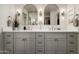 Bathroom featuring double sinks, gray cabinets, gold hardware and two decorative mirrors at 8068 E Del Trigo Rd, Scottsdale, AZ 85258