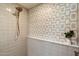 Modern shower featuring a golden shower head and a decorative geometric tile accent wall at 10305 W Campana Dr, Sun City, AZ 85351