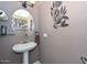 This simple powder room has pedestal sink, decorative metal art and a round mirror at 10806 W Adam Ave, Peoria, AZ 85373