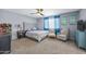 Spacious carpeted bedroom featuring a tufted headboard, ceiling fan, and sitting area at 15410 N 60Th Ave, Glendale, AZ 85306