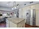 Open kitchen design with granite island, stainless steel refrigerator, and custom cabinetry at 15410 N 60Th Ave, Glendale, AZ 85306