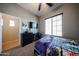 Well-lit bedroom with a large window, ceiling fan, TV, dresser, and doorway to the next room at 16368 W Cortez St, Surprise, AZ 85388
