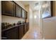 Hallway with tiled floor and dark wood cabinets that feature a stylish display shelf at 16368 W Cortez St, Surprise, AZ 85388