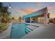 Backyard pool featuring clean blue water, a Baja shelf, lush greenery, and a shaded patio lounge area at 16368 W Cortez St, Surprise, AZ 85388