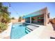Backyard pool featuring clean blue water, a Baja shelf, lush greenery, and a shaded patio lounge area at 16368 W Cortez St, Surprise, AZ 85388