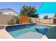 Sparkling pool with in-water seating area, lush landscaping, and a modern wooden privacy screen at 16368 W Cortez St, Surprise, AZ 85388