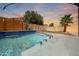 Backyard pool with cascading waterfall feature, decorative lighting, lush landscaping and a colorful sunset at 16368 W Cortez St, Surprise, AZ 85388