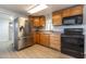 Modern kitchen featuring stainless refrigerator, black appliances, and light colored wood cabinets at 17200 W Bell Rd # 1801, Surprise, AZ 85374