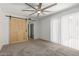 Carpeted bedroom featuring ceiling fan, barn door access to walk-in closet, and sliding glass door to small patio at 1822 S River Dr, Tempe, AZ 85281