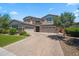 Beautiful home exterior with a stone facade, three-car garage, and a well-manicured front yard with pavers at 20198 E Rosa Rd, Queen Creek, AZ 85142