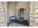 Inviting front porch with stone columns, a bench, a decorative rug, and a wood front door at 20198 E Rosa Rd, Queen Creek, AZ 85142