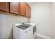 A laundry room with modern appliances and dark wood cabinets above the appliances at 20198 E Rosa Rd, Queen Creek, AZ 85142