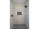 Marble tiled shower with black fixtures, a shower niche, and contrasting dark mosaic tile on the floor at 2790 W Cholla St, Apache Junction, AZ 85120