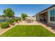 A beautiful backyard featuring a well-maintained lawn, brick patio, and outdoor seating with views of a tranquil pond at 37456 W Vera Cruz Dr, Maricopa, AZ 85138