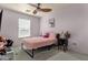 Cozy bedroom with a fluffy pink bed, ceiling fan, a side table, and natural light from a window at 3863 S Posse Trl, Gilbert, AZ 85297