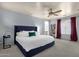 Spacious main bedroom with a large bed, ceiling fan, and a bookcase with an arched alcove to the main bathroom at 3863 S Posse Trl, Gilbert, AZ 85297