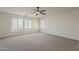 Bright bedroom showcasing plush carpet, multiple windows with modern shutters, and ceiling fan at 40759 W Bravo Dr, Maricopa, AZ 85138