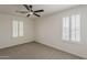This bedroom features carpet, a ceiling fan, and natural light from shuttered windows at 40759 W Bravo Dr, Maricopa, AZ 85138