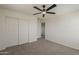 This is a carpeted bedroom with a ceiling fan, closet, and white doors at 40759 W Bravo Dr, Maricopa, AZ 85138