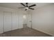 Carpeted bedroom featuring a ceiling fan, closet, and white trim at 40759 W Bravo Dr, Maricopa, AZ 85138