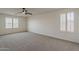 Inviting bedroom featuring plush carpet, neutral walls, ceiling fan, and bright shuttered windows at 40759 W Bravo Dr, Maricopa, AZ 85138