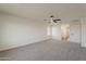 Large, bright bonus room featuring neutral carpet, a ceiling fan, and entry doors at 40759 W Bravo Dr, Maricopa, AZ 85138