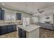 Open kitchen with a center island, navy cabinets, and flows into the living area at 40759 W Bravo Dr, Maricopa, AZ 85138