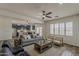 Comfortable living room with a grey sofa, ceiling fan, kitchen access, and bright natural light at 40759 W Bravo Dr, Maricopa, AZ 85138