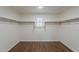 Spacious walk-in closet showcasing hardwood floors, a window, and shelving at 40759 W Bravo Dr, Maricopa, AZ 85138