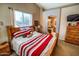 Comfortable bedroom with a view to the bathroom, a large window, a dresser, and a mounted TV at 6731 S 37Th Dr, Phoenix, AZ 85041