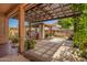 Covered back patio with ample shade, featuring a hot tub under a pergola and lush landscaping at 7413 W Southgate Ave, Phoenix, AZ 85043