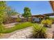 Landscaped backyard with artificial grass, a hot tub under a pergola, and mature trees and plants at 7413 W Southgate Ave, Phoenix, AZ 85043